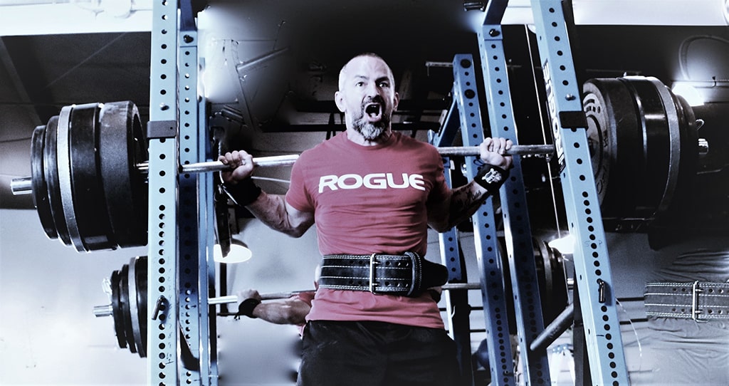 S2 Method Stewart Breeding in red Rogue brand tshirt performing squats with heavy weight on the bar