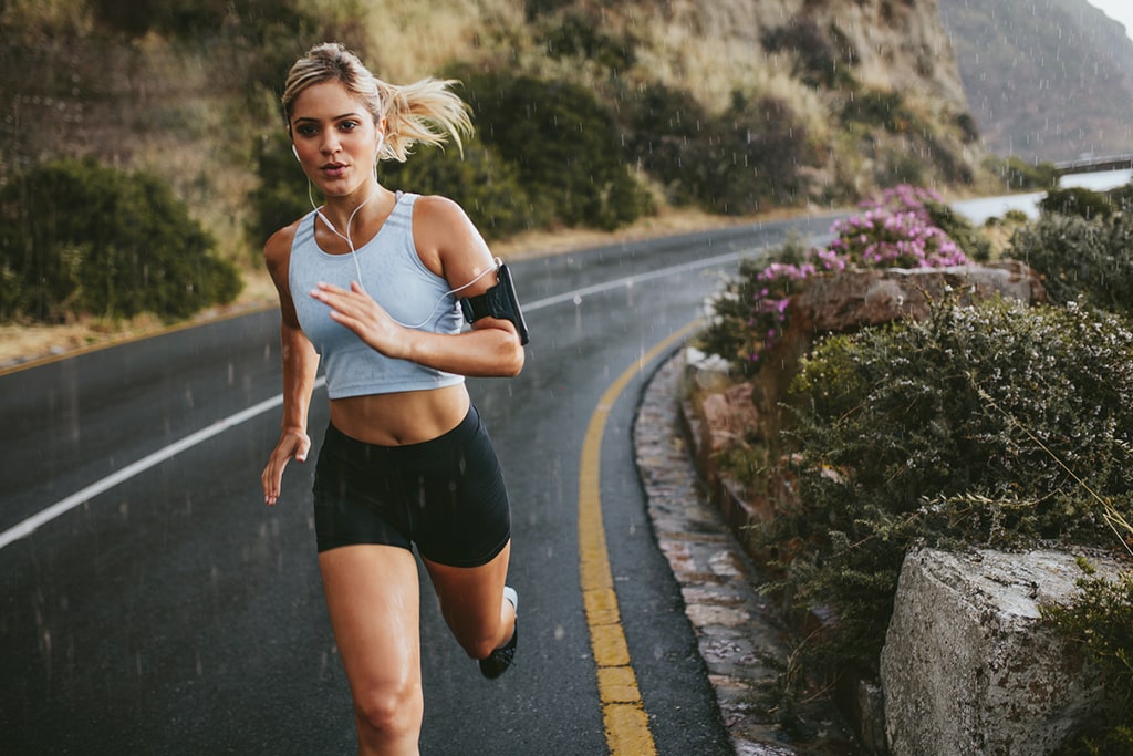 S2 Method Meditraining Medirunning Female on road running in rain while listening to audio device on earbuds